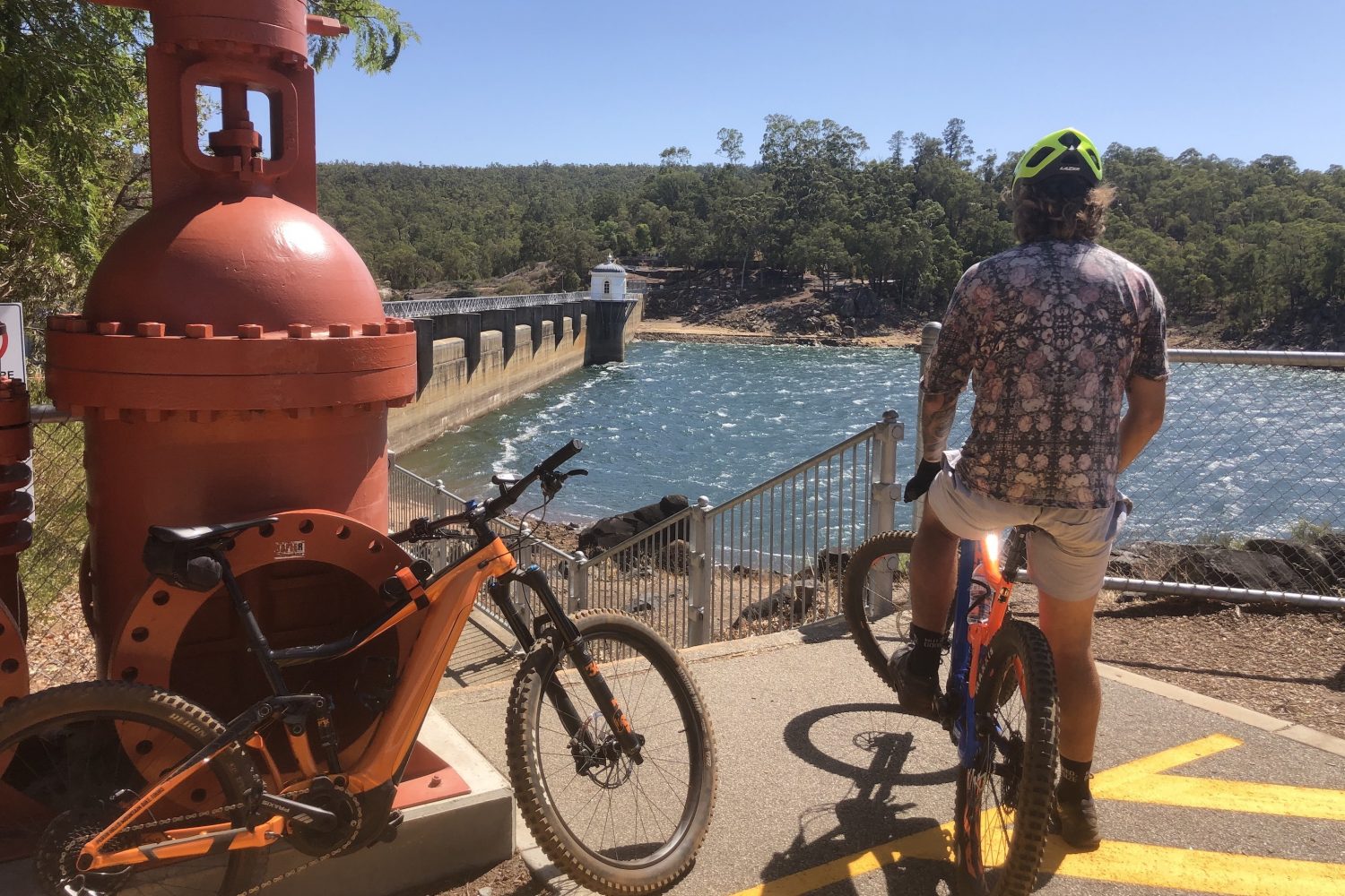 Cyclist sitting on a Giant E Mountain Bike looking over at the Mundaring Weir on a Perth Hills Mountain Bike Tour .