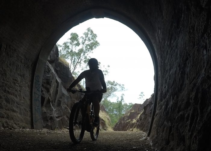 Cyclist Riding Giant E Mountain Bike into Swan View Tunnel in the John Forrest Nation Park on the Railway Heritage Trail on a Perth Hills Mountain Bike Tour.