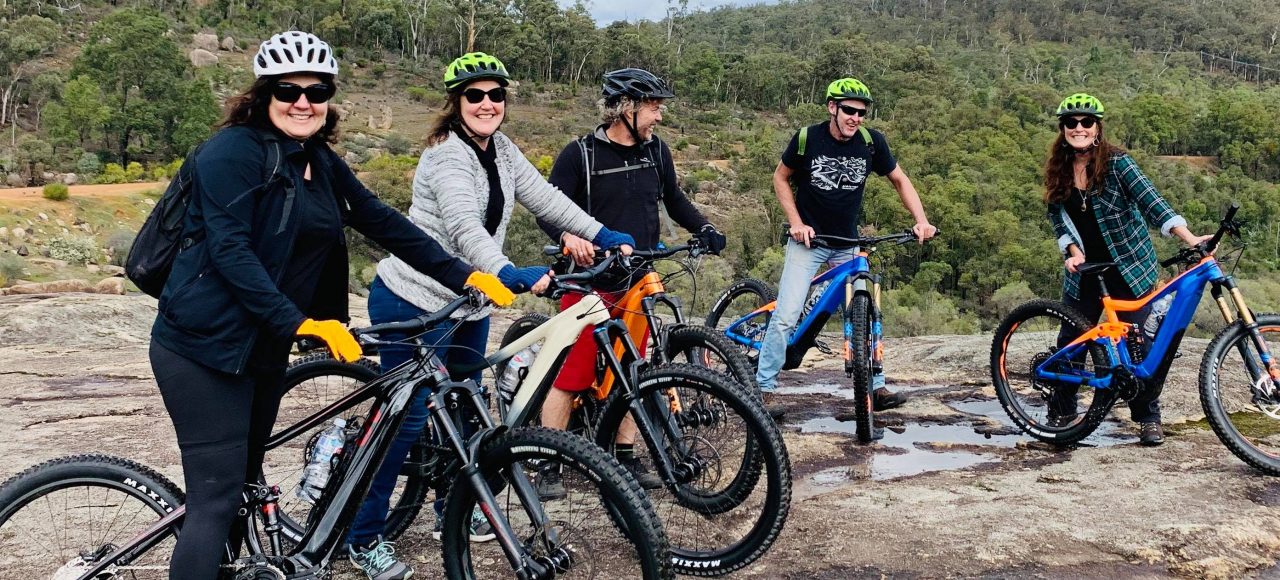 Group of friends all sitting on the Giant E Bikes on a Tailor made Perth Hills Mountain Bike Tours , photo taken on Rock in John Forrest National Park.