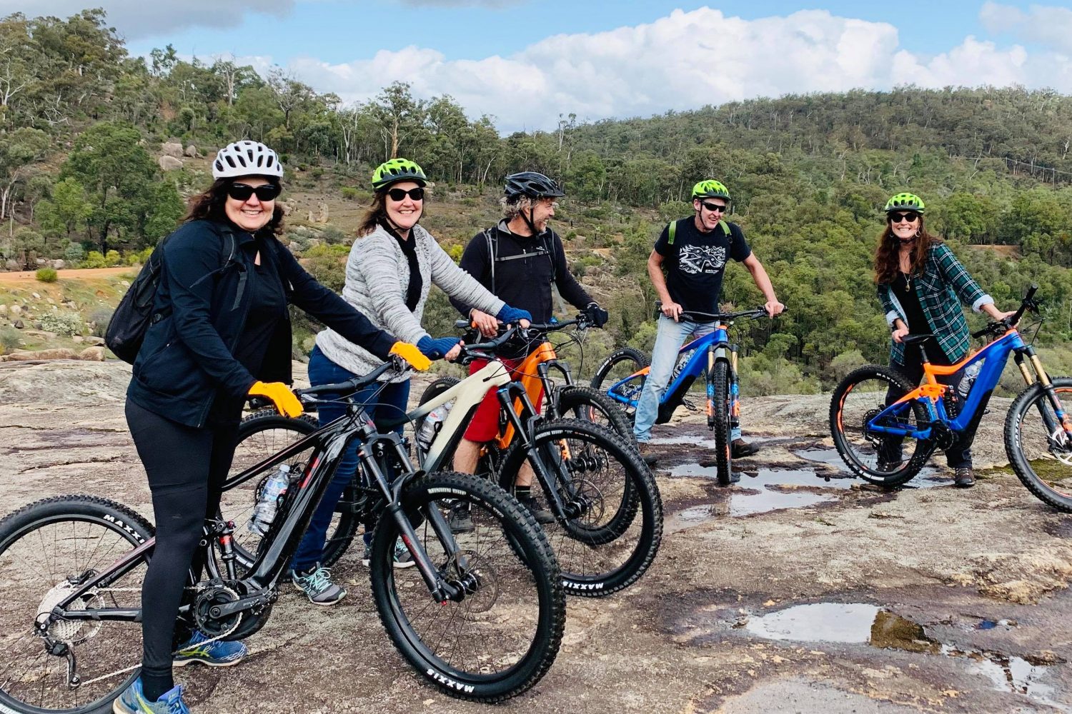 Group of friends all sitting on the Giant E Bikes on a Tailor made Perth Hills Mountain Bike Tours , photo taken on Rock in John Forrest National Park.